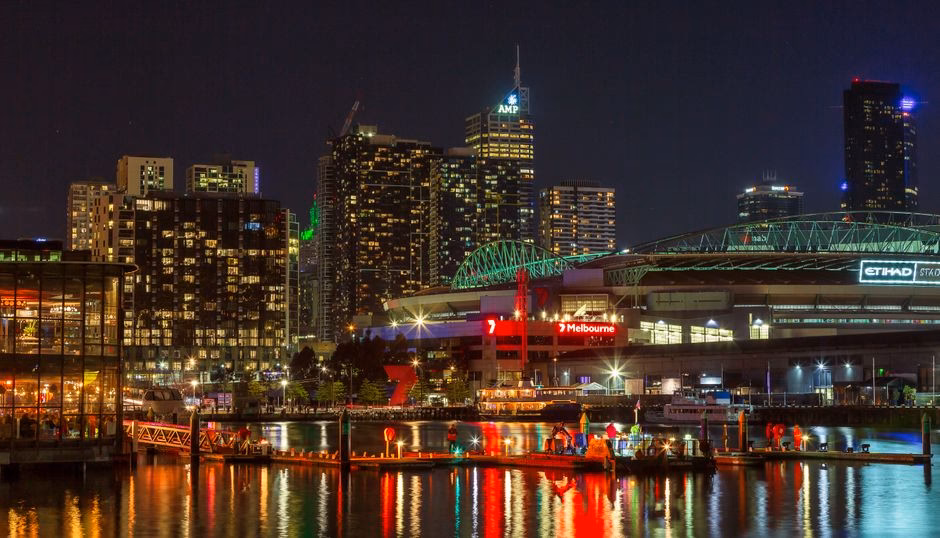 Illuminated Melbourne waterfront cityscape at night showcasing vibrant urban life and architecture.
