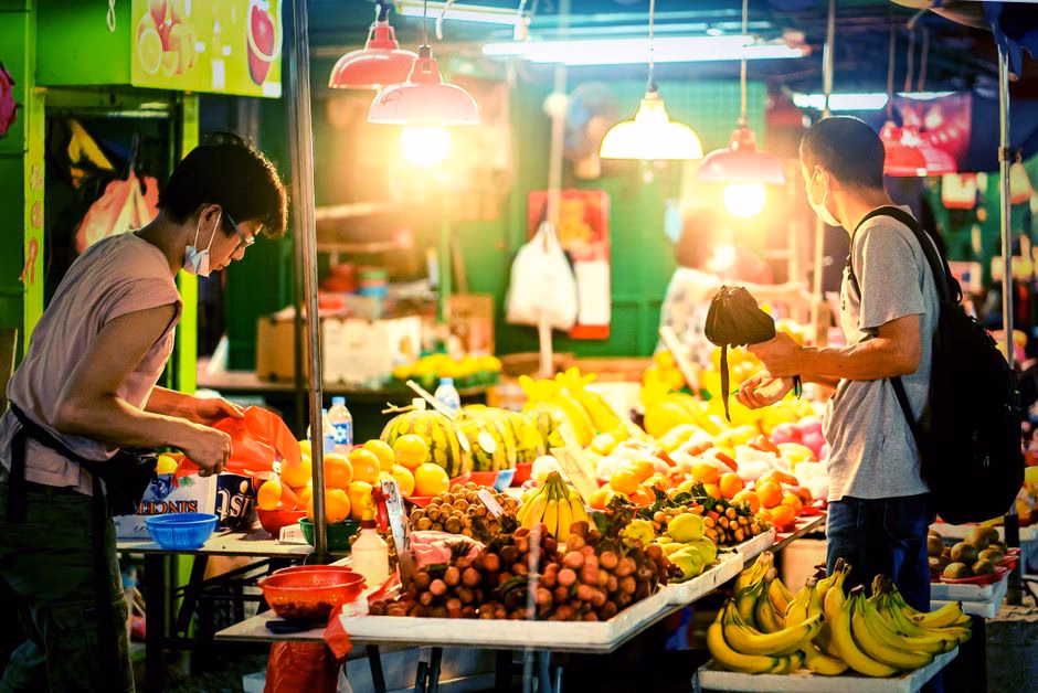 Vibrant Hong Kong night market scene with vendors selling fresh fruits.