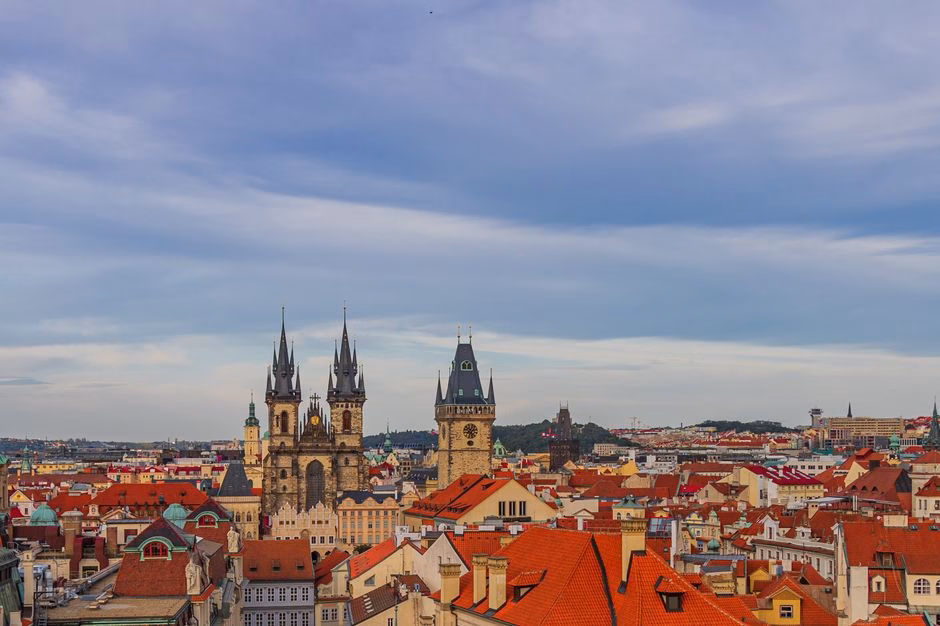 A scenic aerial view of Prague's Old Town Square featuring iconic historic towers under a vibrant sky.