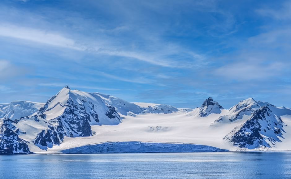 Breathtaking view of rugged snowy mountains under a clear blue sky in Antarctica.