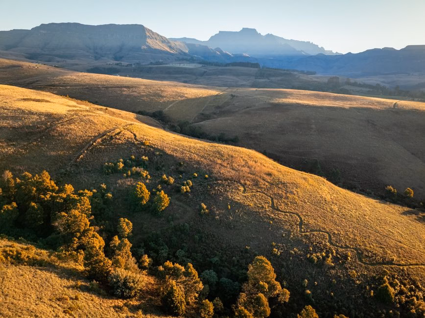 Stunning aerial landscape of rolling hills with dramatic lighting in the Drakensberg Mountains, South Africa.