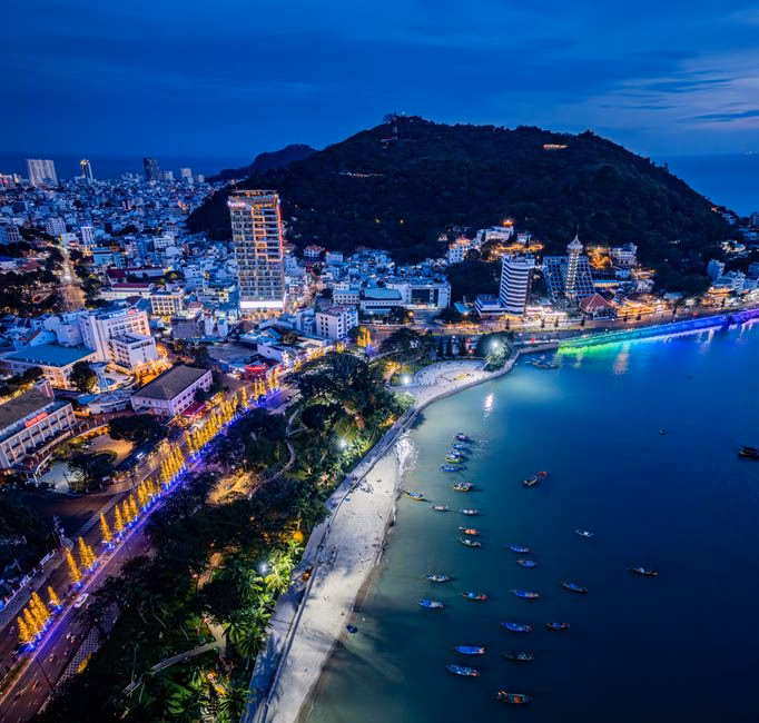 A breathtaking aerial view of a coastal city with vibrant lights at dusk.