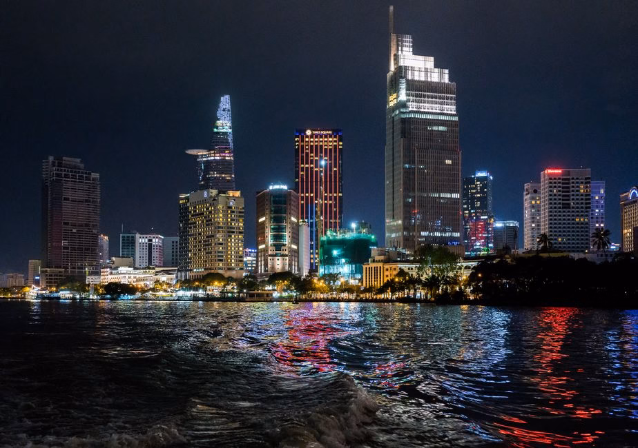 Beautiful night view of Ho Chi Minh City skyline with illuminated skyscrapers reflecting on the water.