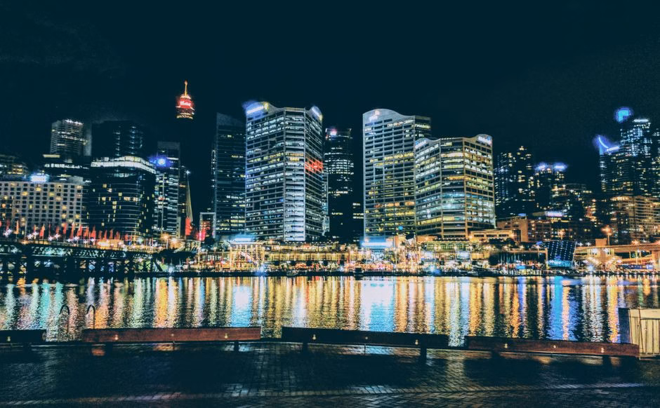 Stunning night view of Sydney's CBD skyline reflecting on the harbor waters, vibrant city lights.