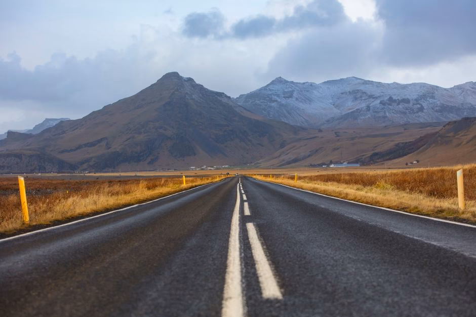 A long, empty road through a stunning mountain landscape in autumn, ideal for travel themes.