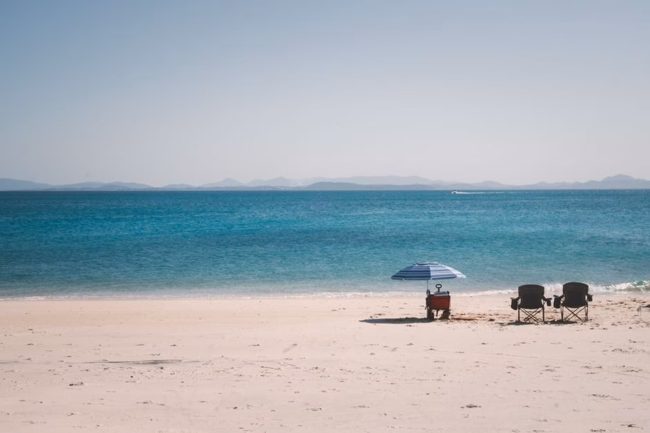 Serene beach scene with chairs and umbrella on The Keppels, QLD, Australia.