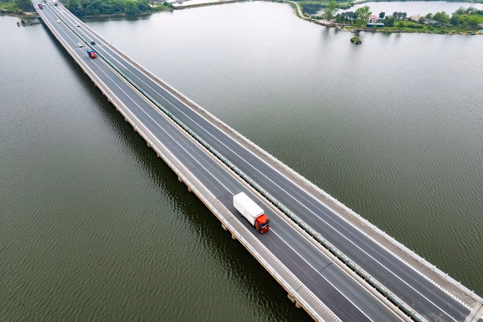 Aerial shot of a bridge with vehicles crossing over a serene water body, showcasing transportation and infrastructure.