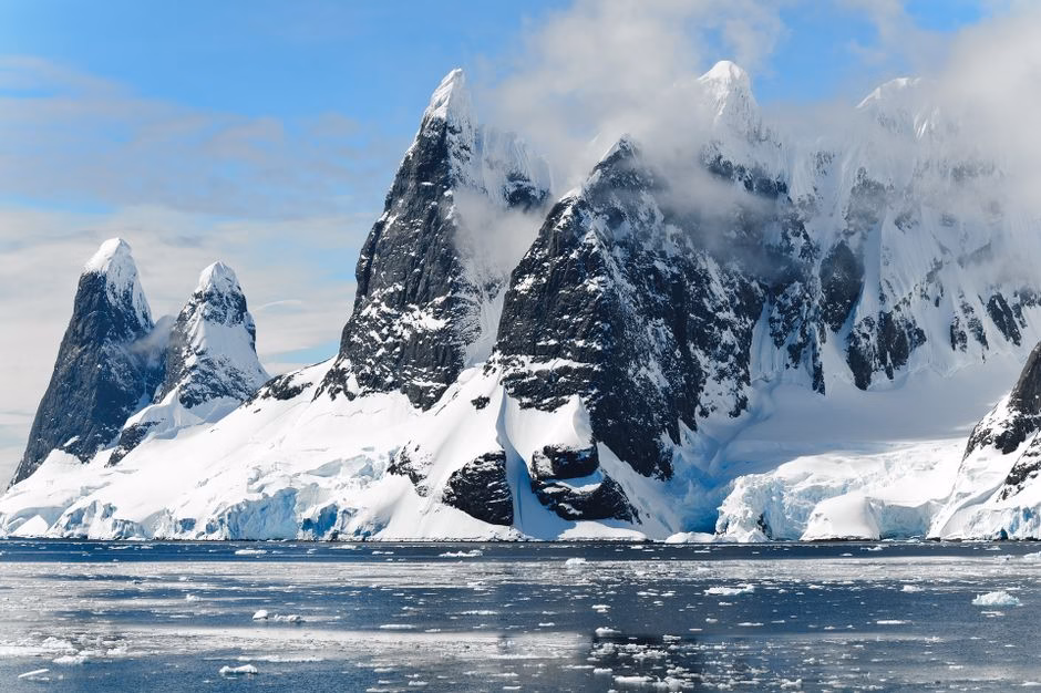 Majestic snowy peaks rise over icy Antarctic waters, showcasing untouched nature.